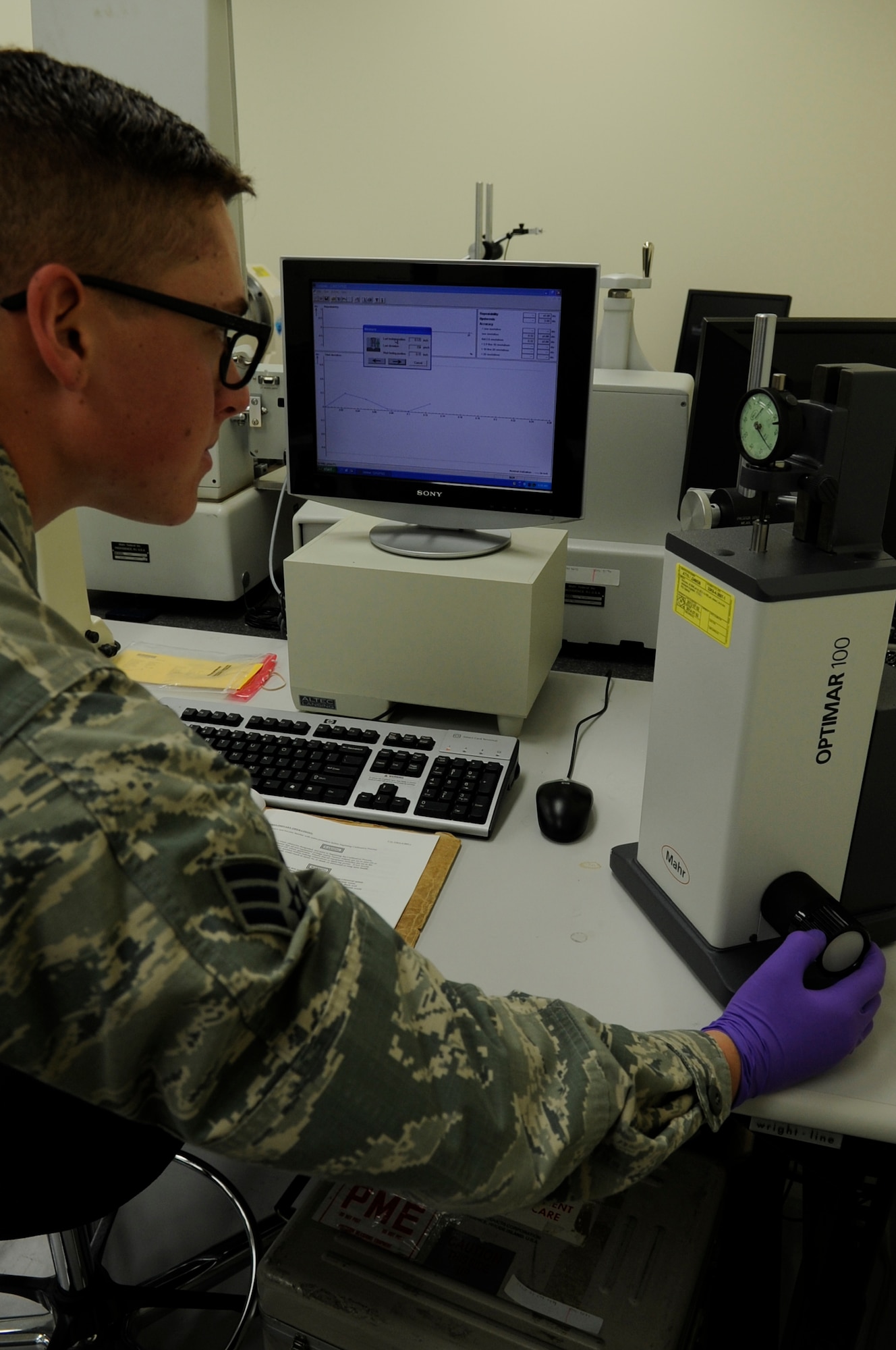 Senior Airman Vince Doll, 18th Component Maintenance Squadron precision measurement equipment laboratory technician, calibrates a dial indicator using an Optimar 100 on Kadena Air Base, Japan, Oct. 3, 2013. The dial is calibrated multiple times to determine its past and present accuracy to keep the instrument precise. (U.S. Air Force photo by Senior Airman Marcus Morris)