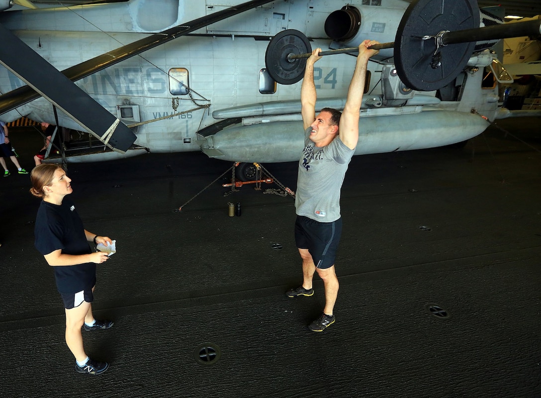 Marine Maj. Albert "AJ" Goldberg, Command Element, 13th Marine Expeditionary Unit, completes a Push Press during "Fight Gone Bad," while 1st Lt. Talya Havice,  CE, 13th MEU keeps score Oct. 13, 2013. "Fight Gone Bad" is a Crossfit workout involving three rounds of five different exercises.The 13th MEU is a Marine Air-Ground Task Force forward-deployed to the U.S. 5th Fleet area of responsibility aboard the Boxer Amphibious Ready Group serving as a sea-based, expeditionary crisis response force capable of conducting amphibious operations across the full range of military operations. (U.S. Marine Corps photo by SSgt. Matt. Orr, Released)