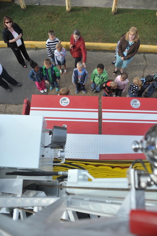 Students from John H. Russell Elementary listen to a fire instructor from the Quantico Fire and Emergency Services examine the components of a fire truck at their on Oct. 8, 2013 for Fire Prevention Week. The students were given the chance to walk around the fire truck and see the different equipment firemen use.