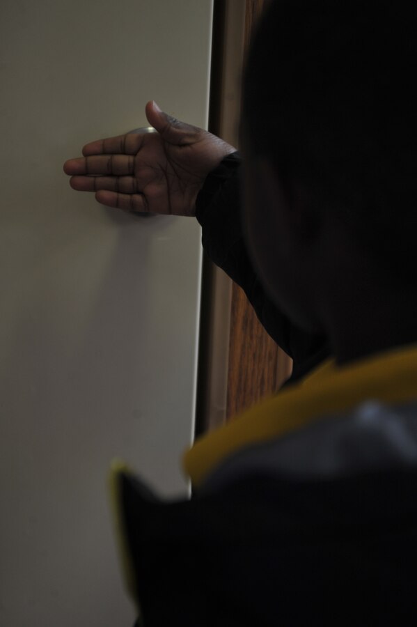 A student from John H. Russell Elementary demonstrates the proper method for checking doors during a fire on Oct. 8, 2013. After the demonstration, the smokehouse simulator the students were in was pumped with harmless smoke and the students used what they learned to escape the house. (Marine Corps photo by Lance Cpl. Cuong Le/ Released)