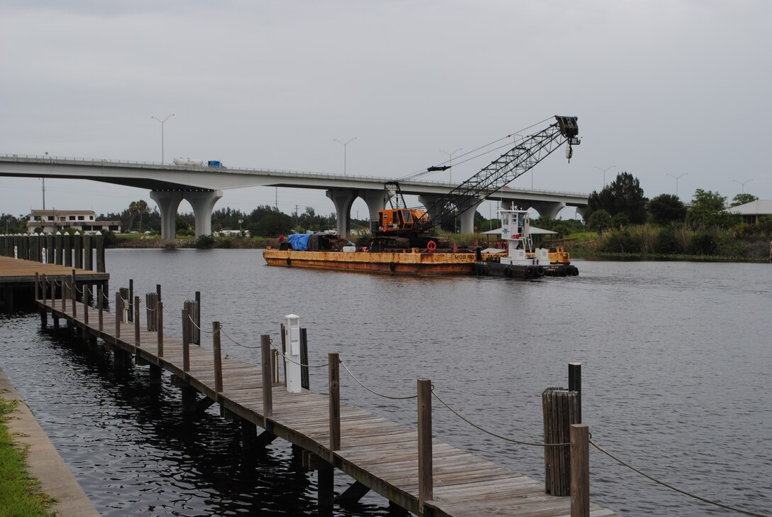 A barge pushes a crane underneath a bridge on the Caloosahatchee River at Moore Haven. The river is part of the 152-mile-long Okeechobee Waterway that allows boaters to travel by water from the Atlantic Ocean to the Gulf of Mexico. 