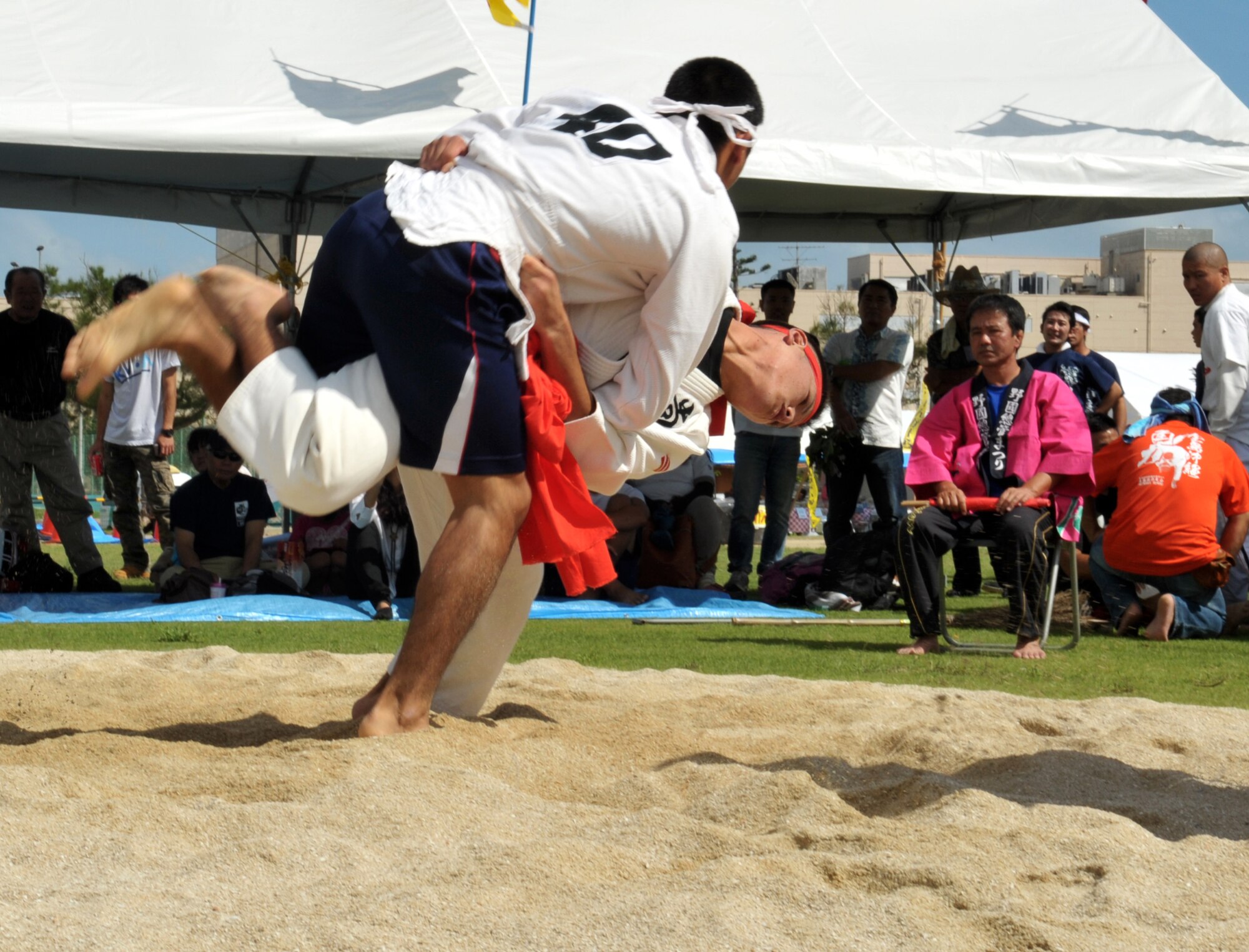 Takahiro Chibana (red player) hurls Toshiki Uechi (white player) in the Kakuriki (Okinawa-style sumo) competition during the 33rd Noguni Sokan Festival in Kadena Kaneku Seaside Park, Japan, Oct. 13, 2013. Kakuriki is a special sumo style which combines judo and wrestling. (Courtesy photo)