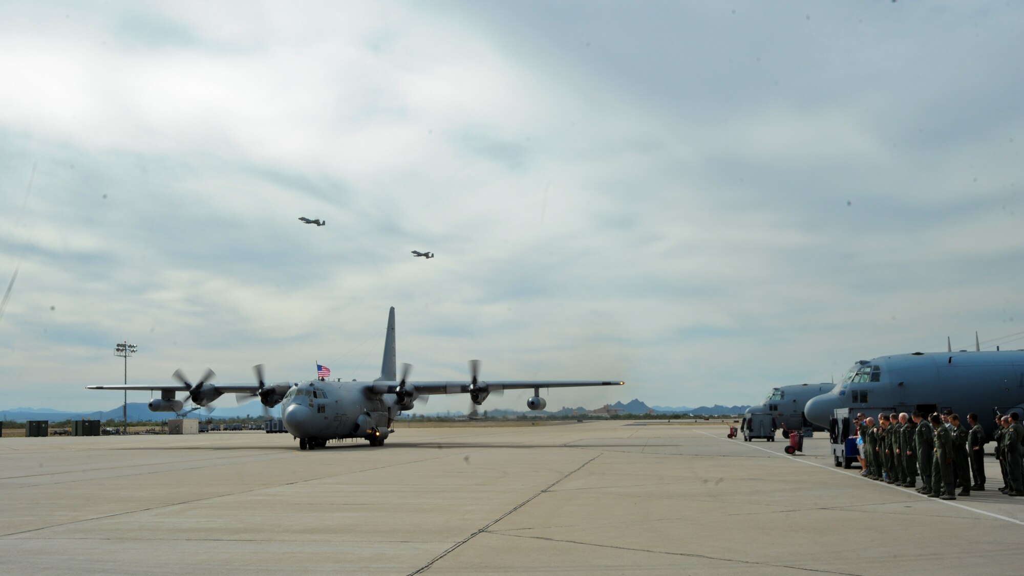 U.S. Air Force Airmen and family members of the 55th Electronic Combat Group, salute while an EC-130H Compass Call aircraft taxis at Davis-Monthan Air Force Base, Ariz., Oct. 7, 2013. The Airmen were welcomed home after a three month deployment by family and friends. (U.S. Air Force photo by Senior Airman Sivan Veazie/Released)