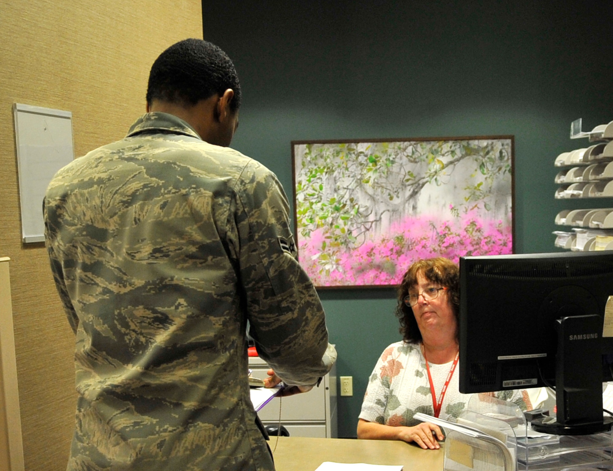Airman 1st Class Adrian Green, 2nd Aerospace Medicine Squadron bioenvironmental engineer, checks in with Marjorie McCullough, Family Health Clinic medical support assistant, on Barksdale Air Force Base, Oct. 11, 2013. Healthcare providers will be able to see a patient every 15 minutes and active-duty Airmen who call between 7 and 7:30 a.m. will receive appointment priority. (U.S. Air Force Photo/Airman 1st Class Benjamin Raughton)
