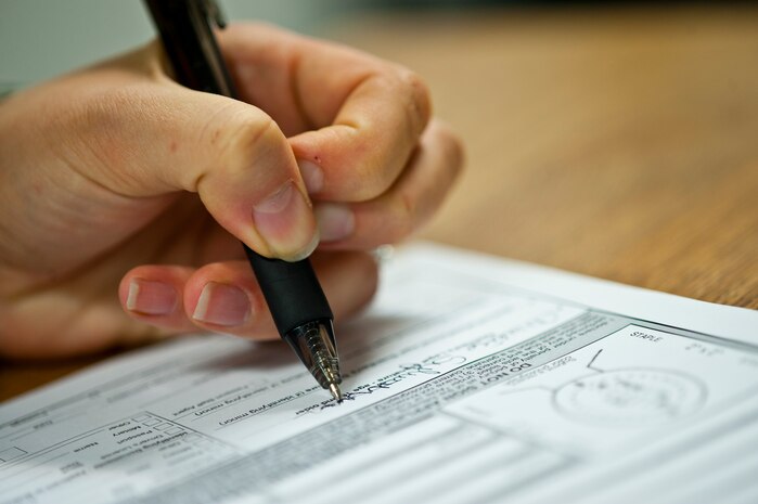 Senior Airman Analise Sylvester, 99th Force Support Squadron customer service technician, fills out an official passport application at the military customer service office Oct. 11, 2013 at Nellis Air Force Base, Nev. Even though the 99th FSS is processing official passports, the Department of State has suspended the final processing of the applications due to the government shutdown. (U.S. Air Force photo by Staff Sgt. Michael Charles)