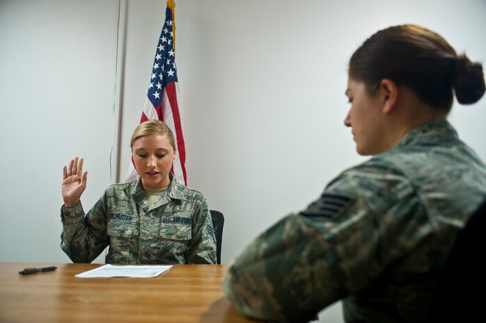 Staff Sgt. Melissa Thomas, 99th Force Support Squadron formal training and passports NCO in charge, administers the oath of allegiance to Senior Airman Analise Sylvester, 99th FSS customer service technician to fulfill passport application requirements  Oct. 11, 2013, at Nellis Air force Base, Nev. The 99th FSS is processing official passport applications throughout the government shutdown.  However, due to the lack of government funding, the Department of State has suspended the final processing of applications.  (U.S. Air Force photo by Staff Sgt. Michael Charles)