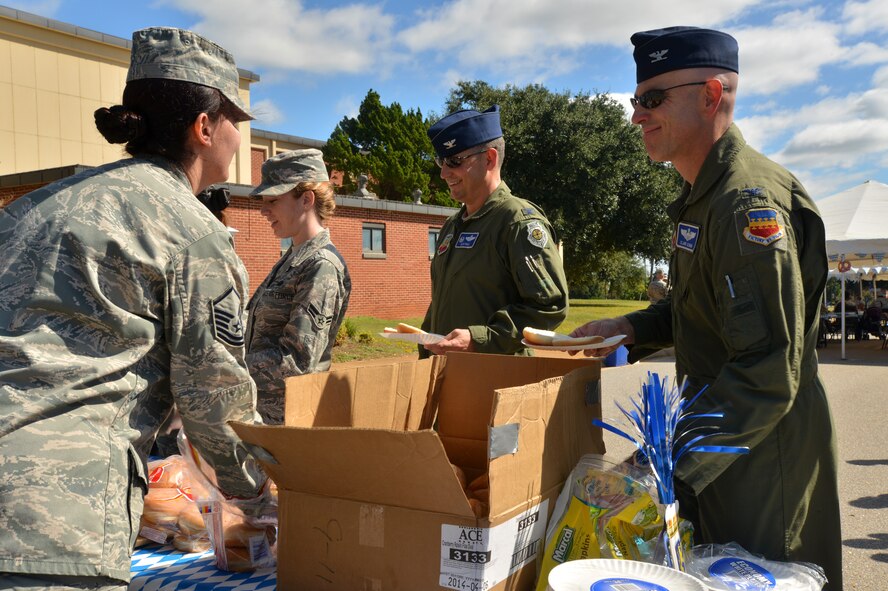 U.S. Air Force Master Sgt. Nancy Barron-Palumbo, 9th Air Force superintendent and additional-duty first sergeant, hands food to Col. Clay Hall, 20th Fighter Wing commander, and Col. Clark Quinn, 20th Fighter Wing vice commander, during a first sergeant appreciation picnic, Shaw Air Force Base, S.C., Oct. 10, 2013. The Oktoberfest-themed picnic was held to celebrate the Enlisted Attic’s grand re-opening; a place for free clothing, uniforms, and household items for E-5 and below and their dependents.  (U.S. Air Force photo by Airman 1st Class Jensen Stidham/Released)