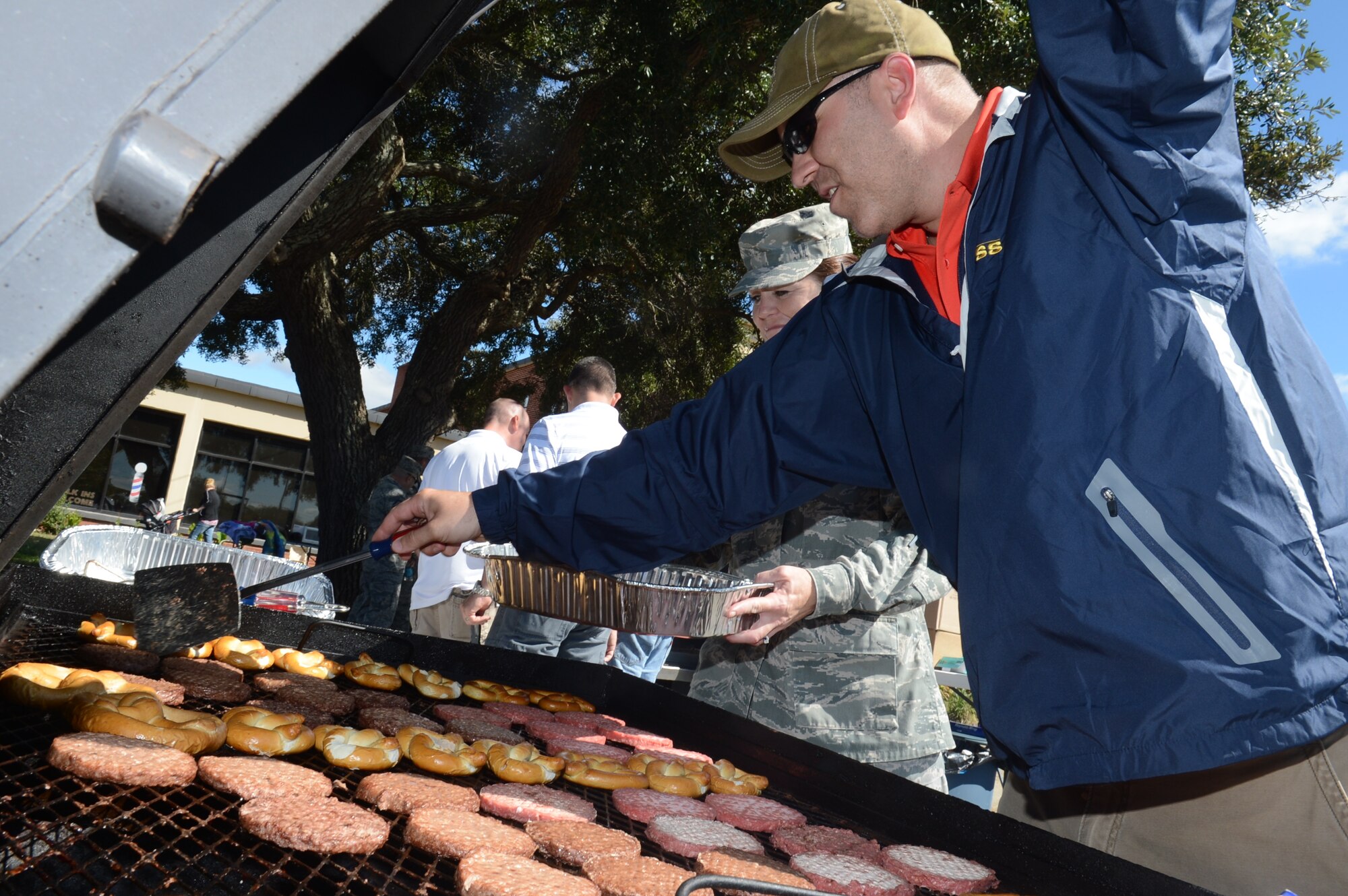 An Airman cooks burgers, brats, and pretzels on the grill for the first sergeant appreciation picnic at Shaw Air Force base, S.C., Oct. 10, 2013. The picnic was held in coordination with the grand re-opening of the Airmen’s Attic. (U.S. Air Force photo by Airman 1st Class Jonathan Bass/Released)