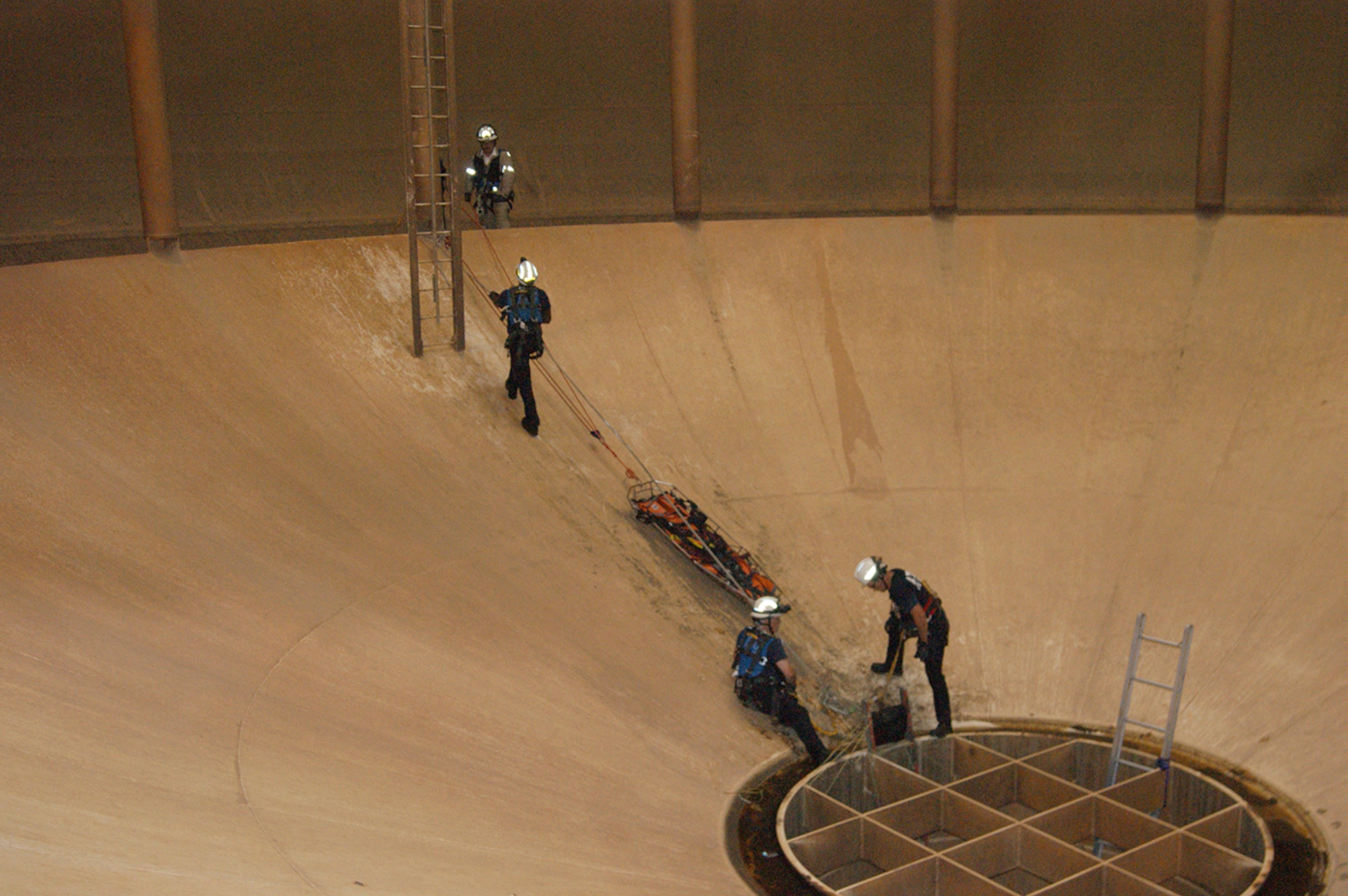 Members of the Arnold Engineering Development Complex (AEDC) Fire and Rescue team are shown here simulating a confined space rescue by moving a rescue basket into the J-6 Large Rocket Test Facility water tank through the main discharge line at the bottom of the photo. This rescue simulation prepares the team for a paint restoration project ongoing inside the water tank. (Photo provided by Josh Cooke)