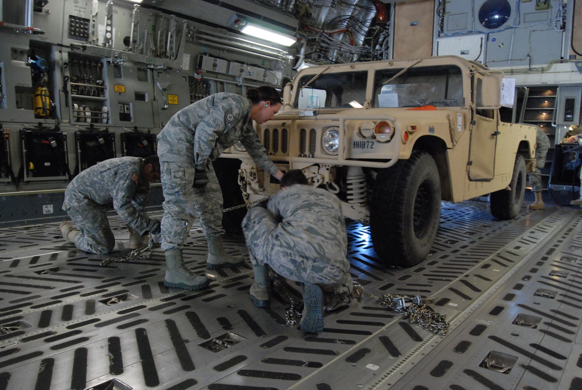 COLORADO SPRINGS, Colo. – Airmen with the 21st Logistics Readiness Squadron secure a vehicle to the floor of a C-17 using tie-down chains Oct. 9. Ensuring cargo is properly secured is crucial to the safety of the aircraft and crew. (U.S. Air Force photo/Michael Golembesky)