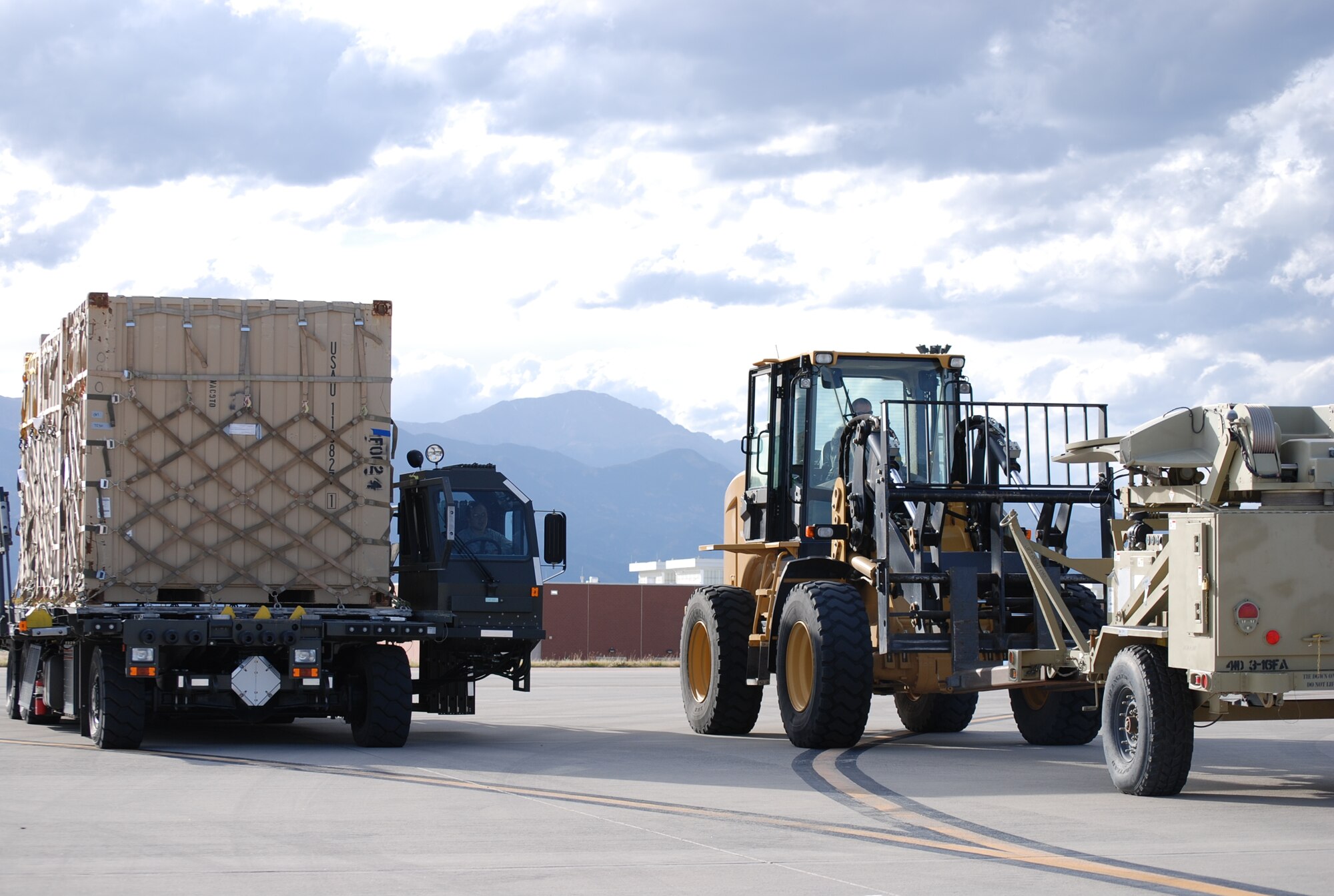 COLORADO SPRINGS, Colo. – Air transportation Airmen from the 21st Logistics Readiness Squadron wait for the signal before approaching the rear of a C-17. The Airmen loaded tons of cargo Oct. 9, a well-orchestrated process that must be executed safely. (U.S. Air Force photo/Michael Golembesky)