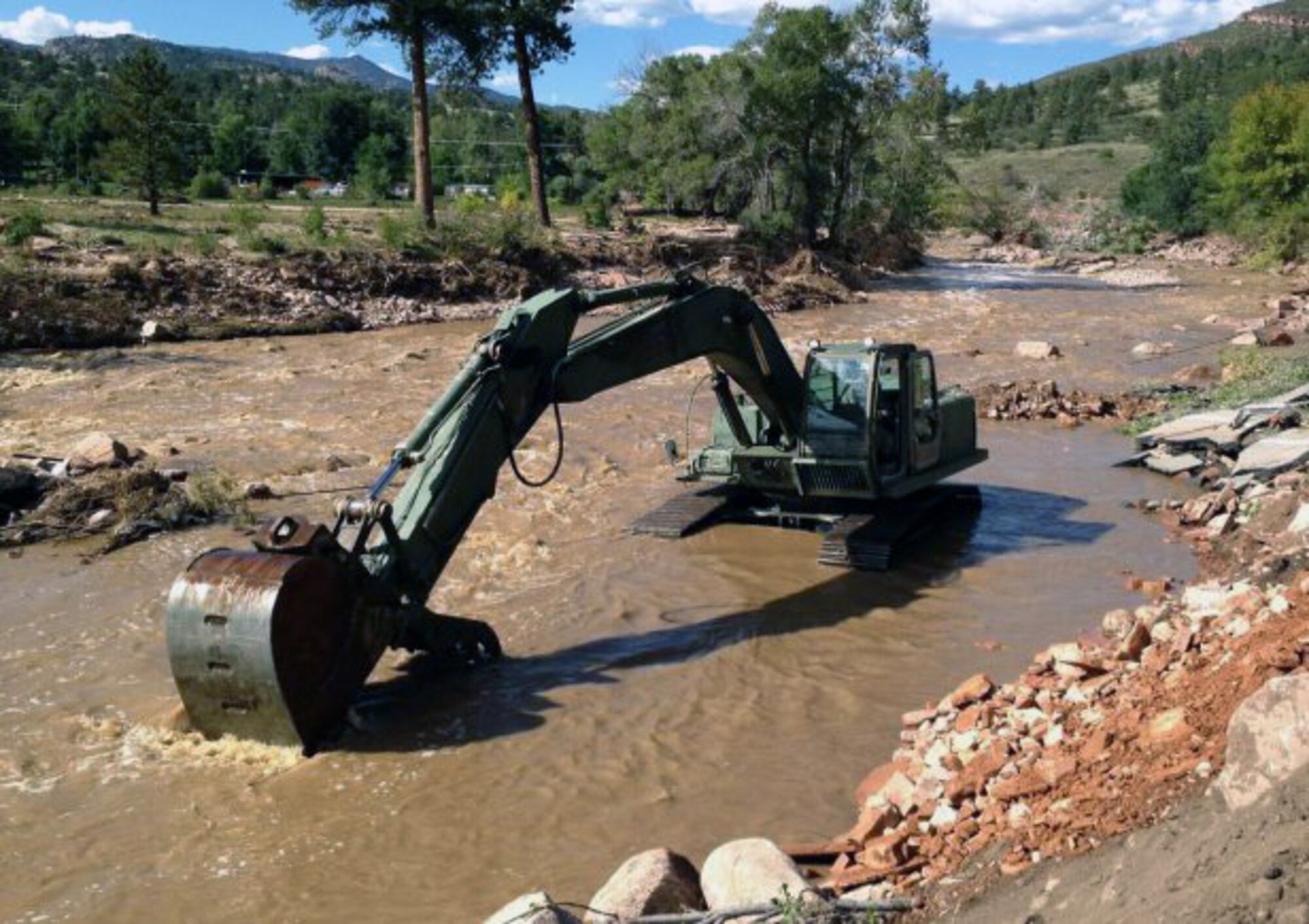 The Texas Army National Guard's 36th Infantry Division's Domestic All-Hazards Response Team-West continues to coordinate assistance requests and support for the Colorado flood relief effort. Pictured here, a military hydraulic excavator works to clear the remainder of a Colorado road after a flood washed it away. (Photo by DART-W Public Affairs Office, 36th Infantry Division)