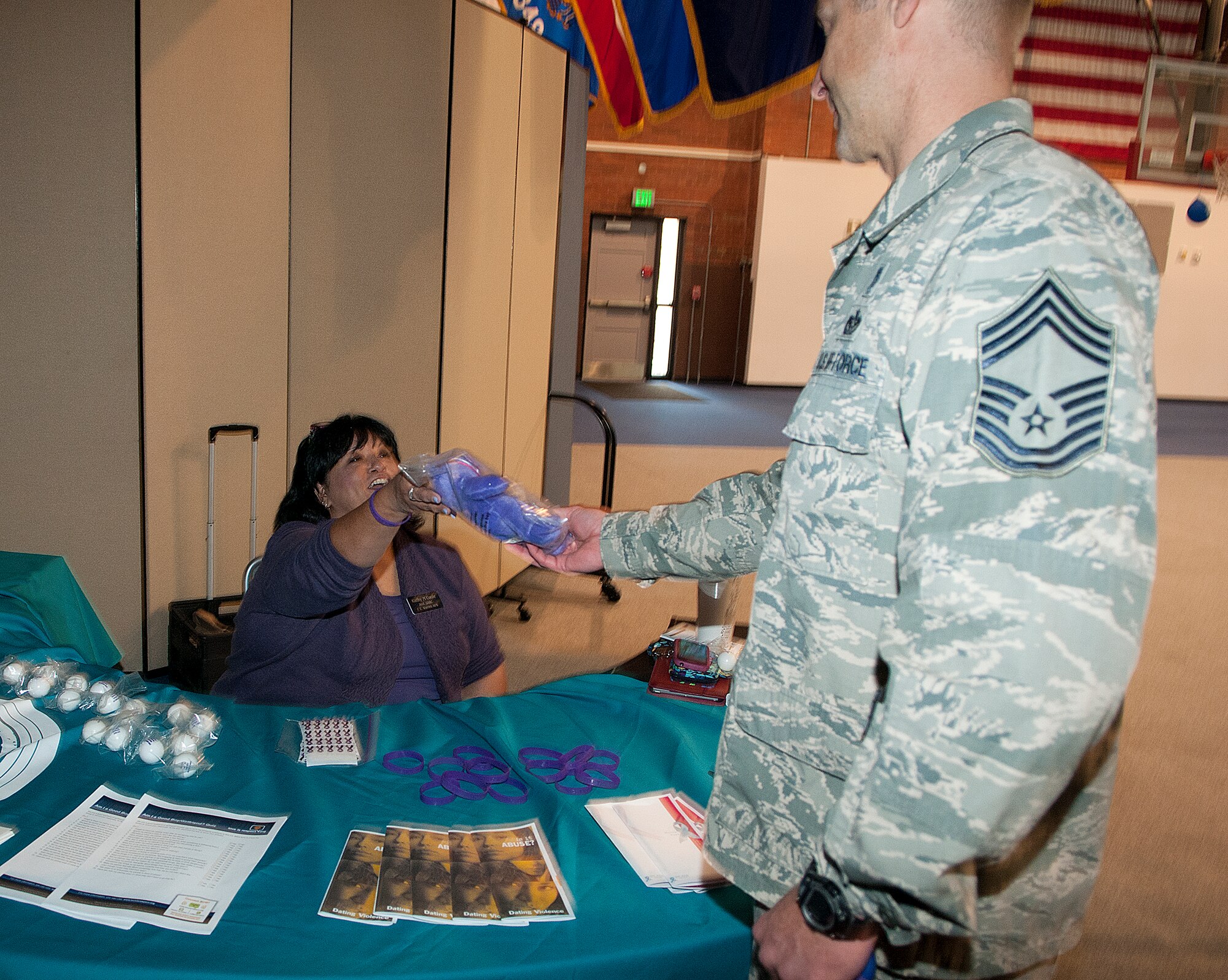 Kathy McCool, 90th Missile Wing Sexual Assault Prevention and Response office, hands Chief Master Sgt. Wayne Stott, 90th Medical Group chief, his prize, a purple teddy bear, after he completed the F.E. Warren Air Force Base Domestic Violence Awareness Confidence Course Challenge in the Fall Hall Community Center Oct. 10, 2013. The event, sponsored by the Domestic Violence Awareness Committee, included informational displays and physical challenges to bring attention to domestic violence. (U.S. Air Force photo by R.J. Oriez)