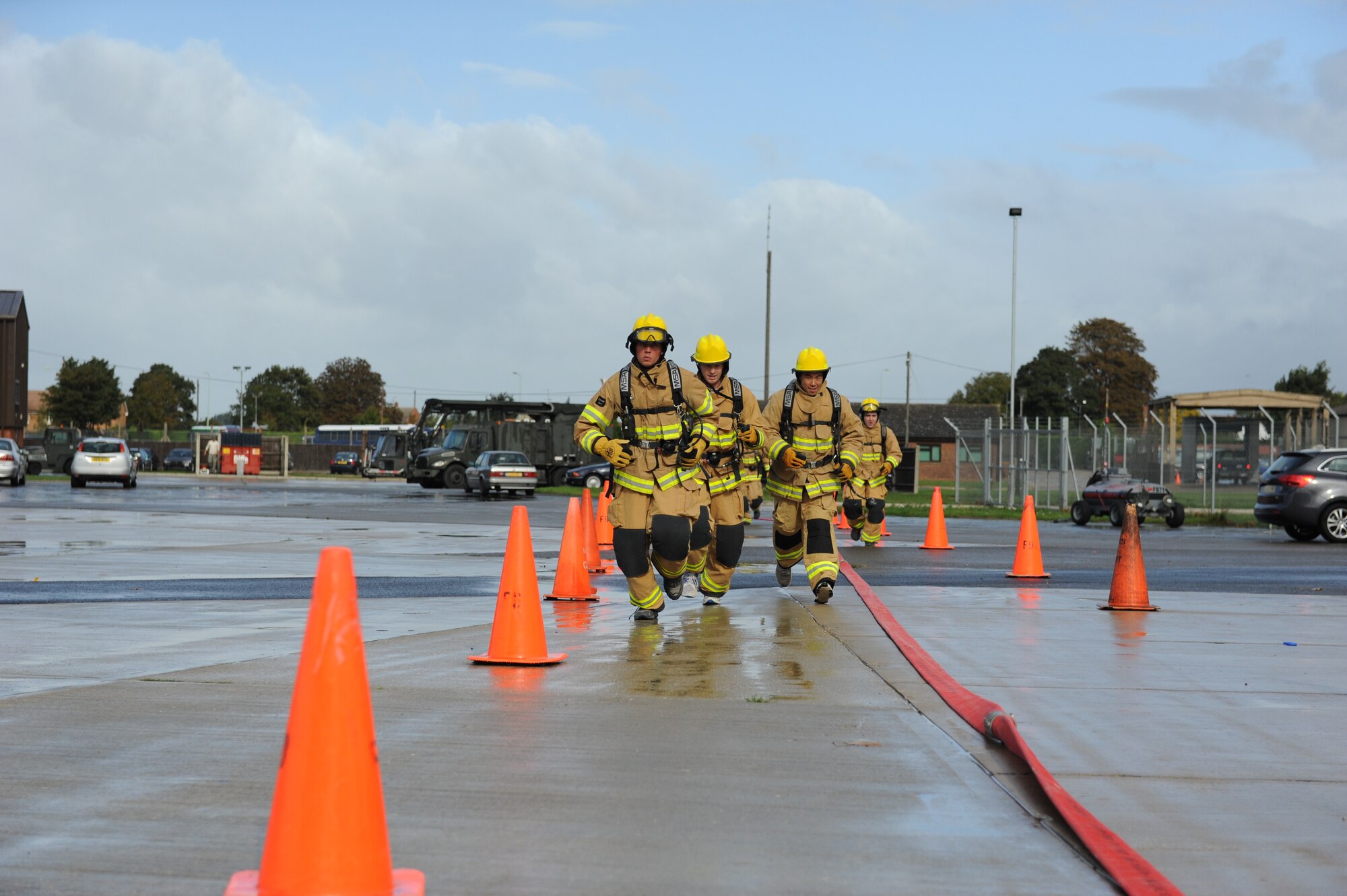 Team Mildenhall members, dressed in firefighter protective gear, compete in the third annual Fire Muster Oct. 10, 2013, on RAF Mildenhall, England. The team just completed the sixth event, a dry hose advance, in which they had to pull a fire hose a few hundred feet. Several teams competed against each other in a series of firefighter-themed events including a bunker drill, dummy drag and a hose assembly. (U.S. Air Force photo by Airman 1st Class Preston Webb/Released)