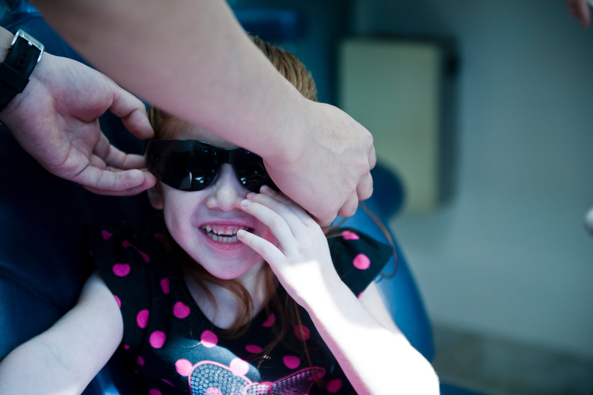 Sunglasses are placed on a military dependent as she prepares for her dental screening Oct. 12, 2013, at Incirlik Air Base, Turkey. Parents and children from across Incirlik Air Base were invited to a special day themed “Little teeth, big smiles” for the children’s chompers to be checked out at the 39th Medical Operation Squadron dental clinic. (U.S. Air Force photo by Senior Airman Daniel Phelps/Released)