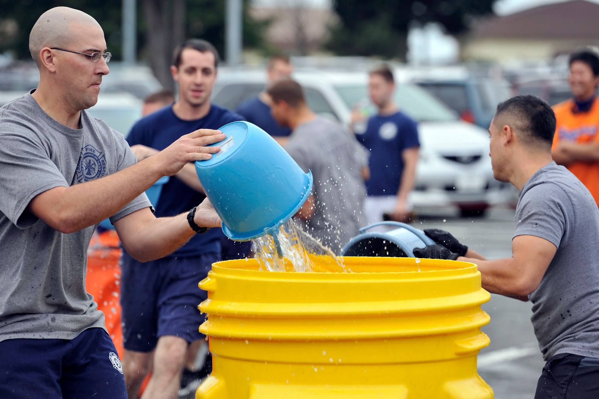 Firefighters from the 35th Civil Engineer Squadron race against the clock and members of the Hachinohe City Fire Department during the opening ceremony of Fire Prevention Week at Misawa Air Base, Japan, Oct. 6, 2013.  During the bucket brigade event, members of each team had to fill their respective barrel with enough water to knock out the ball and stop the clock. (U.S. Air Force photo by Airman 1st Class Zachary Kee)
