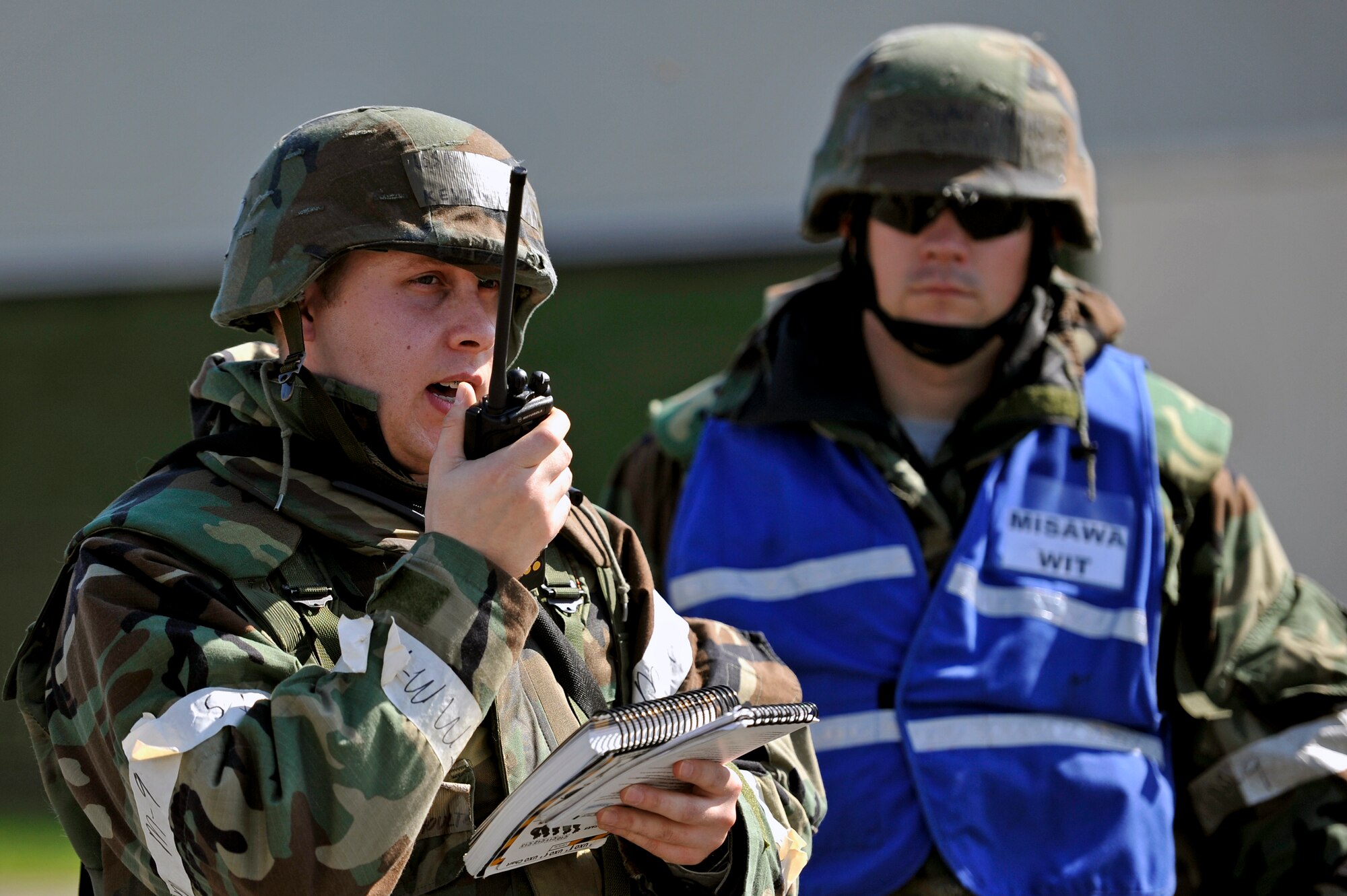 U.S. Air Force Staff Sgt. Kevin Shoultz, 35th Maintenance Squadron precision measurement equipment laboratory technician, calls in simulated unexploded ordnance during an Operational Readiness Exercise as Tech. Sgt. Stephen Morin, 35th Maintenance Group Wing Inspection Team member, looks on at Misawa Air Base, Japan, Oct. 10, 2013. As a WIT member, Morin is responsible for instructing and correcting Airmen if mistakes are made during exercise scenarios. (U.S. Air Force Airman 1st Class Zachary Kee)