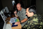 Air Force Capt. John Weldon sits with his Ukrainian partner in the Ground Control Intercept cell at Myrhorod Air Base, Ukraine, participating in Safe Skies 2011, a joint Ukraine, Poland, U.S. aerial exchange event.