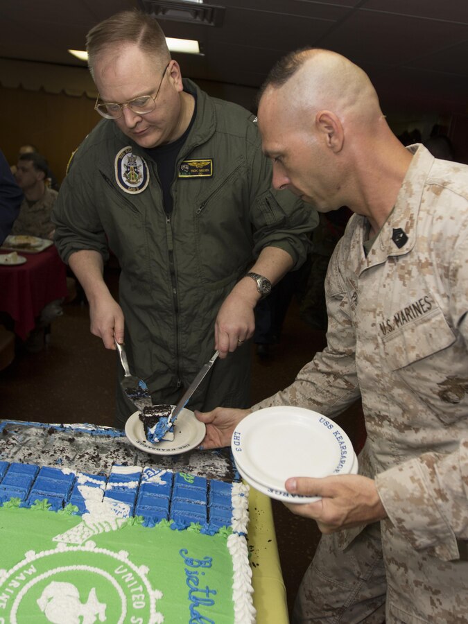 U.S. Navy Capt. Frederick Nielson, USS Kearsarge (LHD 3) commanding officer, and U.S. Marine Corps Sgt. Maj. Todd M. Parisi, 26th Marine Expeditionary Unit (MEU) sergeant major, plate pieces of cake during a cake cutting ceremony to honor the birthdays of the U.S. Marine Corps and U.S. Navy, in the mess deck of the USS Kearsarge, at sea, Oct. 16, 2013. The 26th Marine Expeditionary Unit is a Marine Air-Ground Task Force forward-deployed to the U.S. 6th Fleet area of responsibility aboard the Kearsarge Amphibious Ready Group serving as a sea-based, expeditionary crisis response force capable of conducting amphibious operations across the full range of military operations. (U.S. Marine Corps photo by Cpl. Kyle N. Runnels/Released)