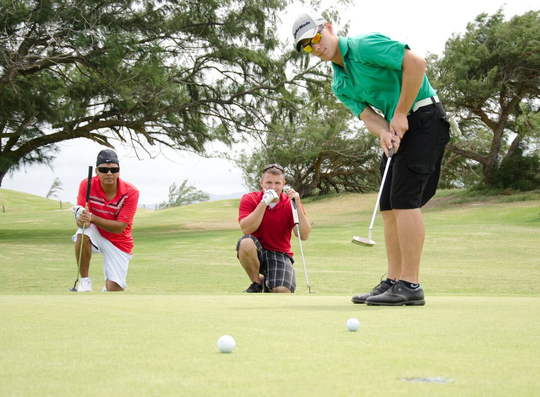 Sgt. Javier Marcano (left), a hazardous material coordinator with Marine Aviation Logistics Squadron 24, and Sgt. Christopher Smith, non-destructive inspection technician, MALS-24, watch Lance Cpl. Sam Milbrandt, an airframes mechanic with MALS-24, putt his ball during the Commander's Cup Golf Classic at the Kaneohe Klipper Golf Course, Sept. 27, 2013. The tournament, which was a four-man scramble format, was open to service members and civilians. (U.S. Marine Corps photo by Kristen Wong)