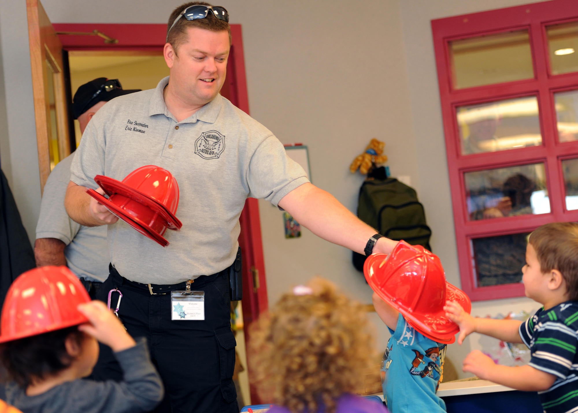 ALTUS AIR FORCE BASE, Okla. – Eric Kinman, 97th Civil Engineer Squadron fire inspector, passes out toy firefighter helmets at the Child Development Center Oct. 10, 2013. During Fire Prevention Week, the fire department visited the CDC and other places around Altus AFB to educate children and adults about the importance of fire safety. (U.S. Air Force photo by Senior Airman Jesse Lopez/Released) 