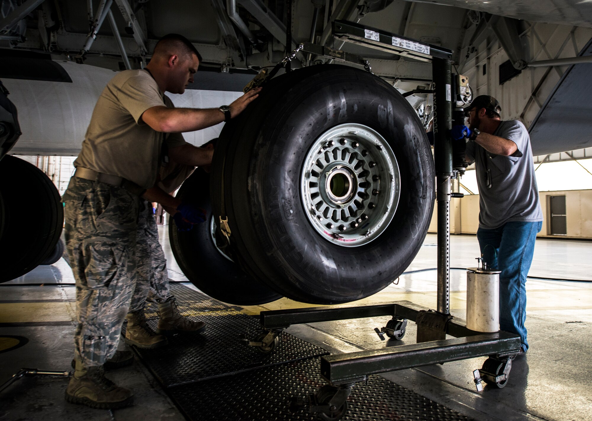 Senior Airman Robert Pearson, 437th Maintenance Squadron crew chief, and Vincent Moseley, 437th MXS aircraft maintainer, remove a worn tire from a C-17 Globemaster III while the aircraft is lifted off the ground by jacks Oct. 7, 2013, at Joint Base Charleston, S.C. A team of eight crew chiefs used six jacks to raise a C-17 Globemaster III off the ground to change a tire and inspect the gears. (U.S. Air Force photo/ Senior Airman Dennis Sloan)