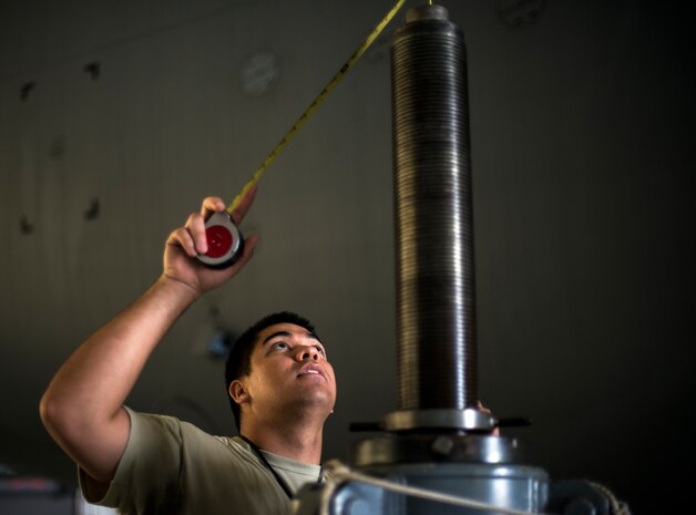 Staff Sgt. Jonathan Quintanilla, 437th Maintenance Squadron crew chief, measures the distance between an aircraft jack and the aircraft using a tape measure Oct. 7, 2013, at Joint Base Charleston, S.C. A team of eight crew chiefs used six jacks to raise a C-17 Globemaster III off the ground to change a tire and inspect the gears. (U.S. Air Force photo/ Senior Airman Dennis Sloan)