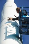 Capt. Bryan Fanick, 5th Maintenance Group maintenance officer, scrapes debris off the Intercontinental Ballistic Minuteman Missile static display at the main gate of Minot Air Force Base, Oct. 13. Fanick, along with other volunteers have spent several weekends restoring the static displays on base as part of a renovation initiative. The restoration project needs volunteers from all over base on Saturdays and Sundays through the month of October until winter time, to restore and repaint the static displays. If anybody is interested in volunteering, please call Fanick at 723-3450 to set up a scheduled shift. (U.S. Air Force photo/Airman 1st Class Apryl Hall)