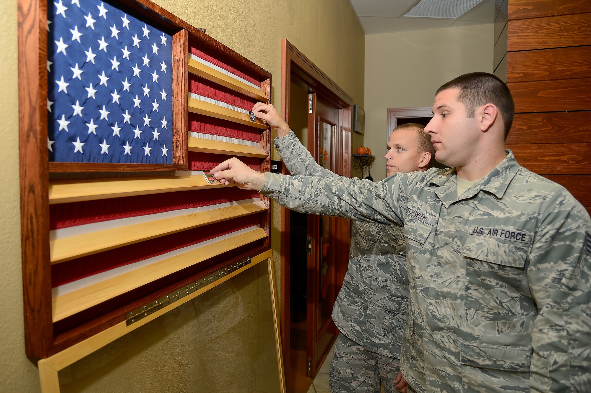 Challenge coins are shown on a table as they are readied for display in a custom case made by Staff Sgts. Thomas Lowe and Bryan Beckwith, 436th Civil Engineer Squadron structures section, Oct. 16, 2013, at Dover Air Force Base, Del . The display was dedicated inside the USO facility in Dover’s passenger terminal.  (U.S. Air Force photo/Greg L. Davis)
