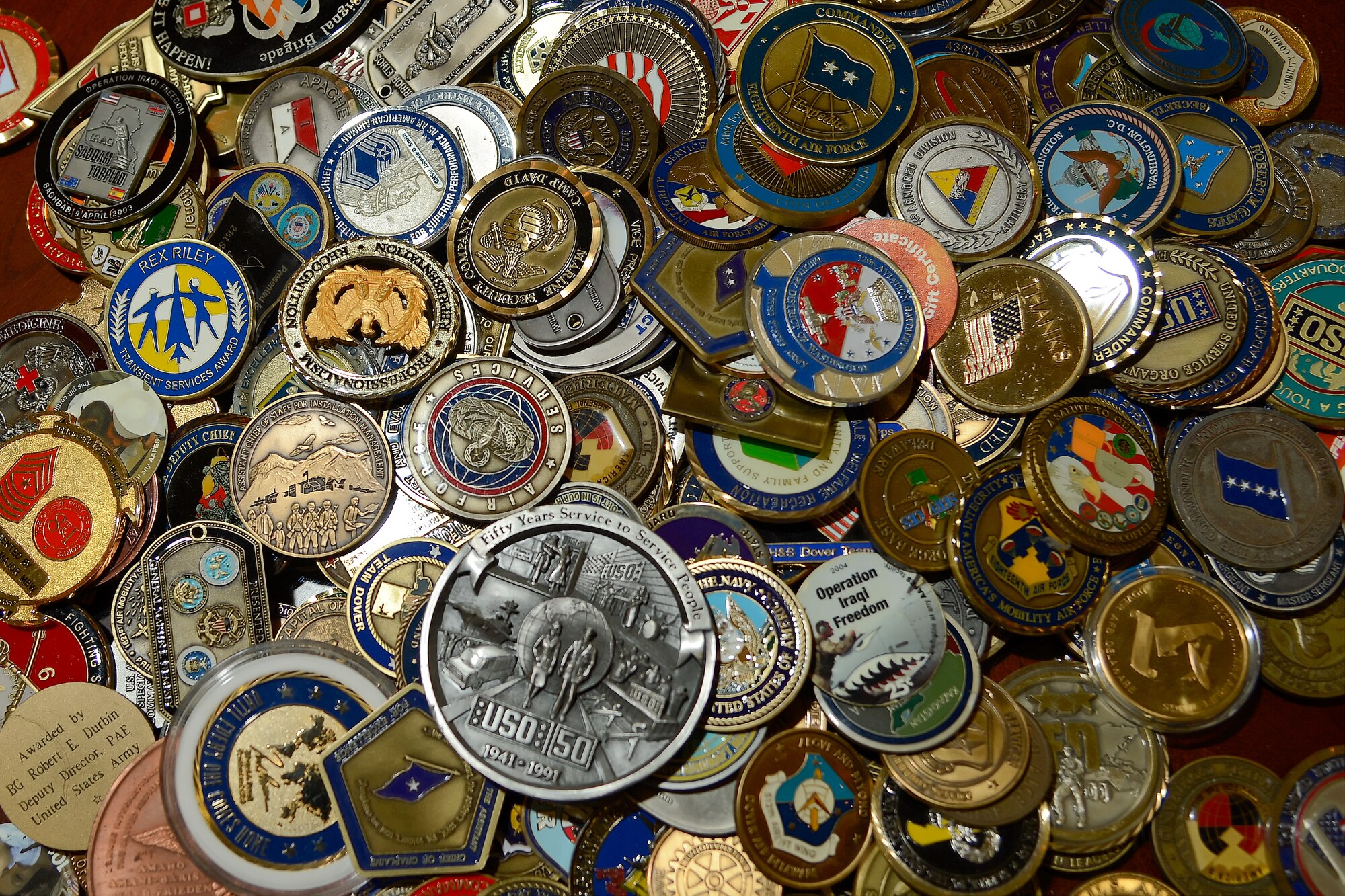 Challenge coins are shown on a table as they are readied for display in a custom case made by Staff Sgts. Thomas Lowe and Bryan Beckwith, 436th Civil Engineer Squadron structures section, Oct. 16, 2013, at Dover Air Force Base, Del . The display was dedicated inside the USO facility in Dover’s passenger terminal.  (U.S. Air Force photo/Greg L. Davis)