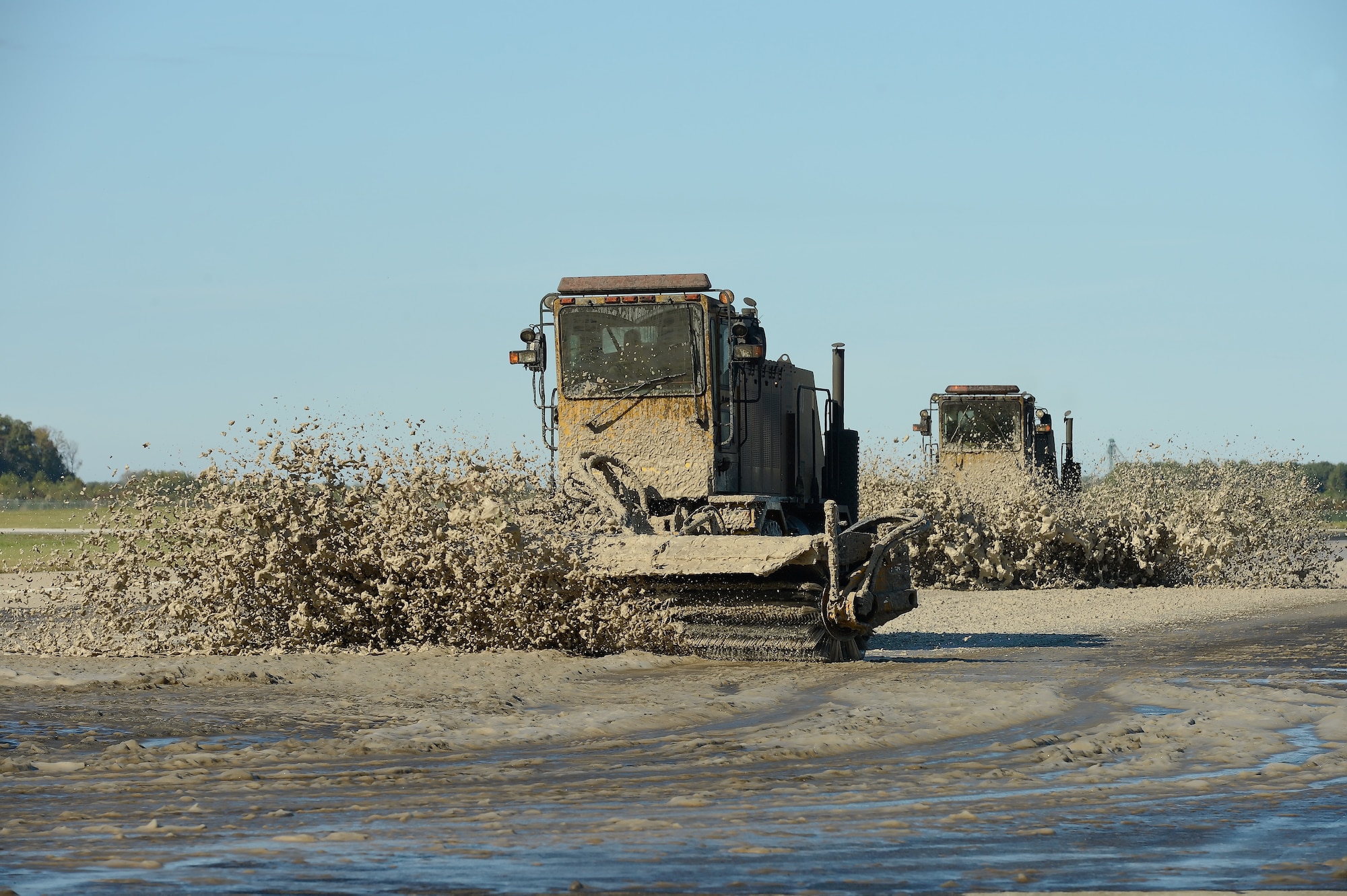 Members of the 436th Civil Engineer Squadron team pavement and heavy equipment operators section, remove rubber from Runway 19 on Oct. 15, 2013, using large Oshkosh tractors with spinning brush attachments at Dover Air Force Base, Del.  A highly concentrated, bio-degradable soap is applied to the runway and scrubbed by the machines before the runway is rinsed off. (U.S. Air Force photo/Greg L. Davis)