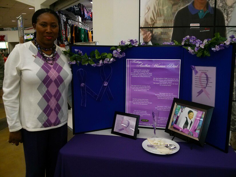 Lynette Lee poses with a display honoring her sister, Sharon C. Murphy. Murphy was killed as a result of domestic violence three days before her 46th birthday. (Courtesy photo/Released)