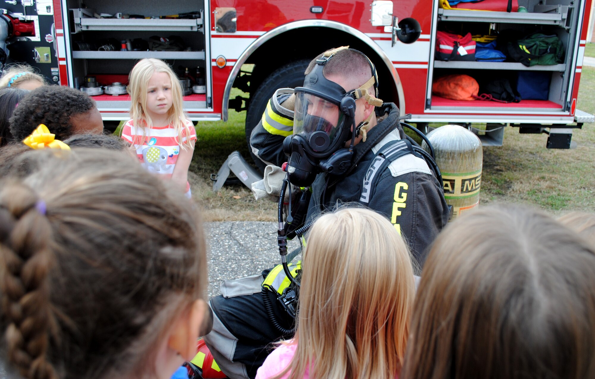 Grand Forks Air Force Base fireman, Travis Zuegin, shows first-graders how his gas mask and other equipment keeps him safe during a fire prevention week learning activity Oct. 8, 2013, at Eielson Elementary on Grand Forks AFB, N.D.  The demonstration of firefighter equipment and fire truck displays were part of several activities that took place during this year’s Fire Prevention Week. (U.S. Air Force photo/Staff Sgt. Luis Loza Gutierrez) 
