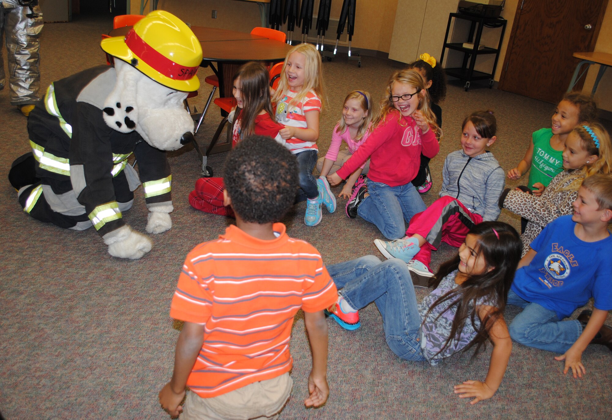 Sparky the Fire Prevention Mascot surprises students at Eielson Elementary by quickly hitting the floor during a meet and greet at the school Oct. 8, 2013. During the meet and greet Sparky demonstrated several fire safety techniques such as staying low to floor in order to avoid breathing smoke during a fire.  The meet and greets with Sparky were part of several activities that took place during this year’s Fire Prevention Week. (U.S. Air Force photo/Staff Sgt. Luis Loza Gutierrez) 