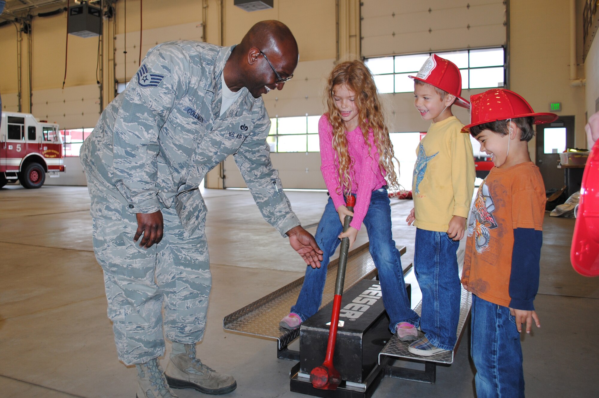 (From right to left) Josiah and Seth Niblack, watch as their sister, Alayna, finds out how heavy a fireman’s sledge hammer really is while Staff Sgt. Aaron Coleman, fire inspector, lends a hand during an open house at the firehouse on Grand Forks Air Force Base, N.D., Oct. 11, 2013. The open house was the culminating event of this year’s Fire Prevention Week. (U.S. Air Force photo/Staff Sgt. Luis Loza Gutierrez) 


