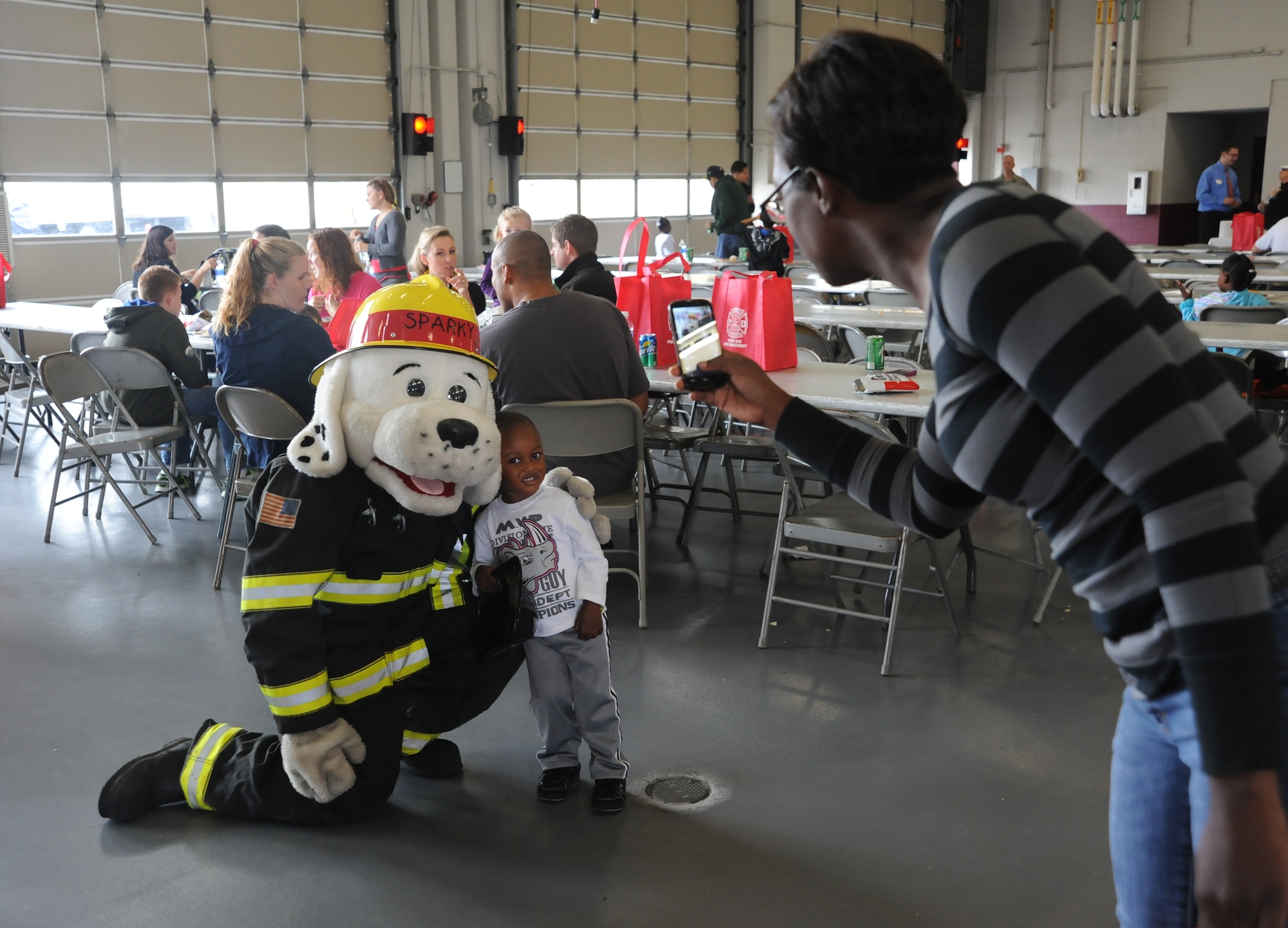 Aiden Cox poses with Sparky the fire dog while his mother Capt. Tiny Cox, 436th Airlift Wing Judge Advocate office, takes their photo during the Military Appreciation Picnic Oct. 12, 2013, at the fire department on Dover Air Force Base, Del. The picnic offered military families free food and activities. (U.S. Air Force photo/Staff Sgt. Elizabeth Morris)