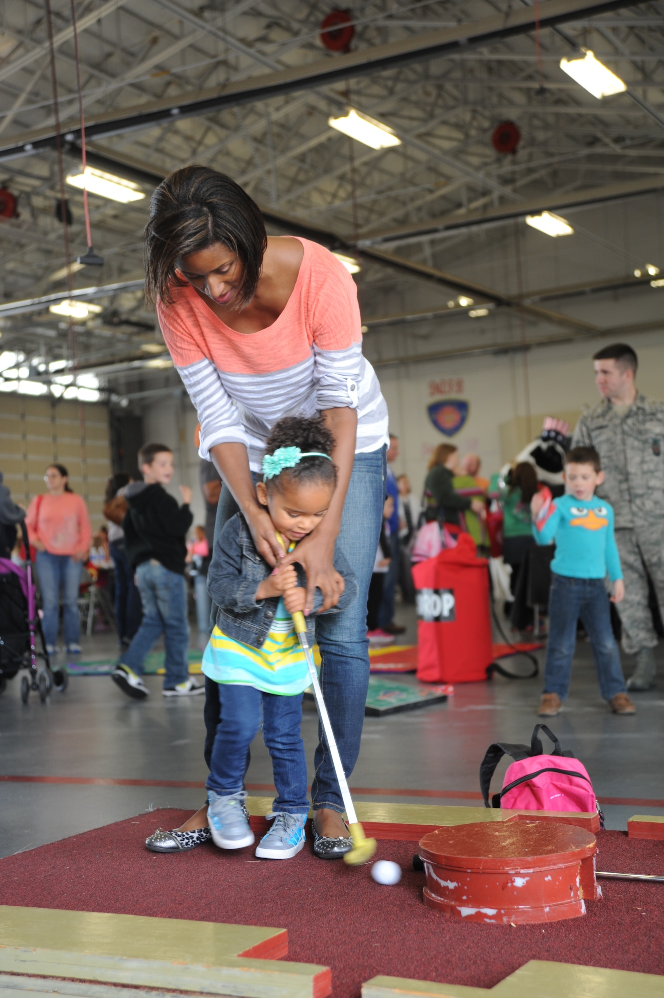 Khloe Wright plays mini-golf at the Military Appreciation Picnic with the help of her mother, Master Sgt. Shakeera Wright, 436th Medical Group, Oct. 12, 2013, at the fire department on Dover Air Force Base, Del. The picnic offered military families free food and activities including bounce houses, face-painting and corn hole. (U.S. Air Force photo/Staff Sgt. Elizabeth Morris)