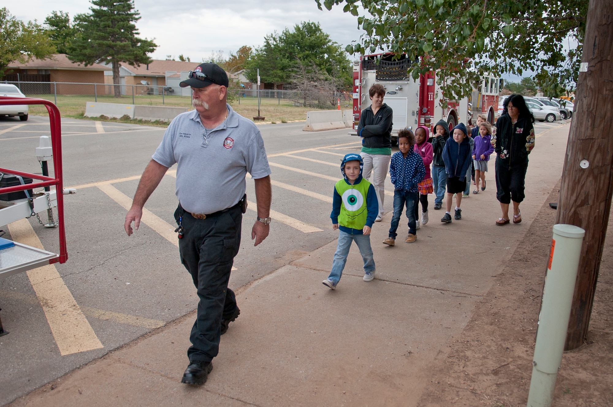 ALTUS AIR FORCE BASE, Okla. – Mr. Billy Allday, 97th Civil Engineer Squadron fire chief, leads a class of L. Mendel Rivers Elementary School students to the house-fire prevention simulator Oct. 15. The trailer offers students a variety of life like house fire scenarios in which they learn to prevent and respond to with learned skills. (U.S. Air Force photo by Senior Airman Dillon Davis/Released)