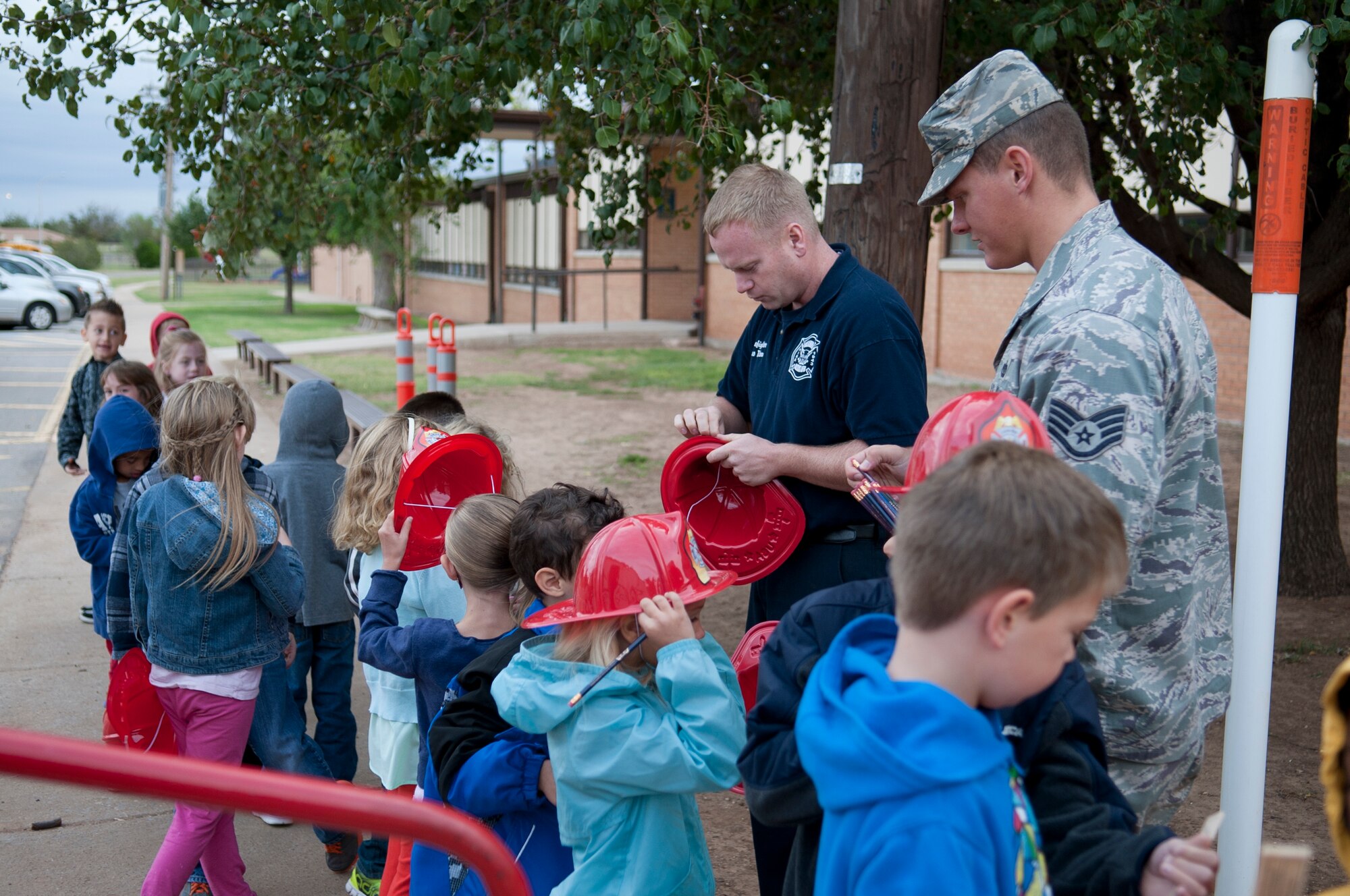 ALTUS AIR FORCE BASE, Okla. – Firefighters assigned to the 97th Civil Engineer Squadron hand out hats, rulers and pencils to children who participate in the house-fire prevention training Oct. 15. The house-fire prevention training allowed children from L. Mendel Rivers Elementary School to learn skills to prevent and respond to house fires. (U.S. Air Force photo by Senior Airman Dillon Davis/Released)