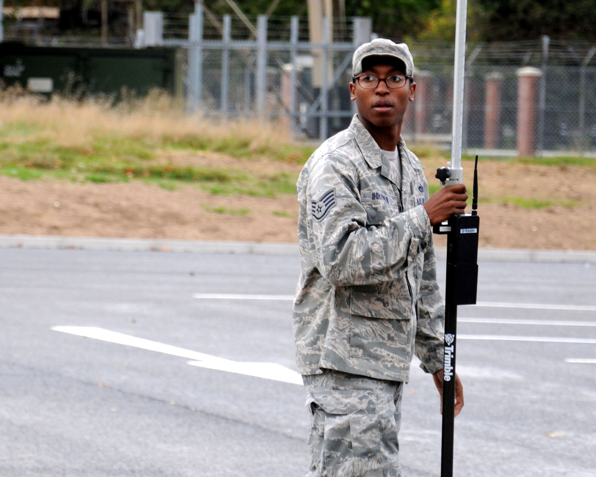U.S. Air Force Staff Sgt. Erik Holloman, 100th Civil Engineer Squadron NCO in charge of geobase (GPS location detector) from Washington, D.C., holds a prism so the controlling station can take points while mapping a parking lot Oct. 9, 2013, on RAF Mildenhall, England. Members of the 100th ARW leadership visited the 100th CES Engineer Assistants shop as part of the “dirty jobs” program. Holloman explained how the 100th CES Engineer Assistants shop provides mapping, drafting and surveying support to keep the installation base map up-to-date.  (U.S. Air Force photo by Gina Randall/Released) 