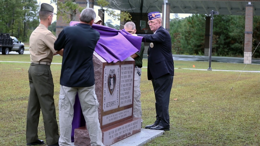 Lt. Col. Leland W. Suttee, Wounded Warrior Battalion-East commanding officer, Grant Beck, Beirut Memorial Chapter 642 Military Order of the Purple Heart commander, retired Lt. Col. Tim Maxwell, the guest speaker, and other guest speakers unveil the Purple Heart Memorial at the WWBn-East barracks aboard Marine Corps Base Camp Lejeune, Oct. 11. Beirut Memorial Chapter 642 Military Order of the Purple Heart donated the memorial to the battalion.
