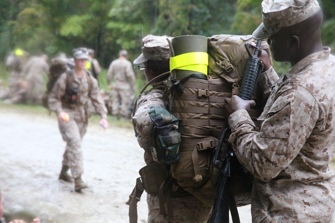 A student with the Field Medical Training Battalion helps another student don her pack aboard Camp Johnson during their eight-mile hike, Oct. 8. When they started, they were argumentative with each other because of the weather, said Petty Officer 3rd Class Paul Johnson, a student with the FMTB, but as they came to the end of the hike, they pulled together and helped motivate each other.


