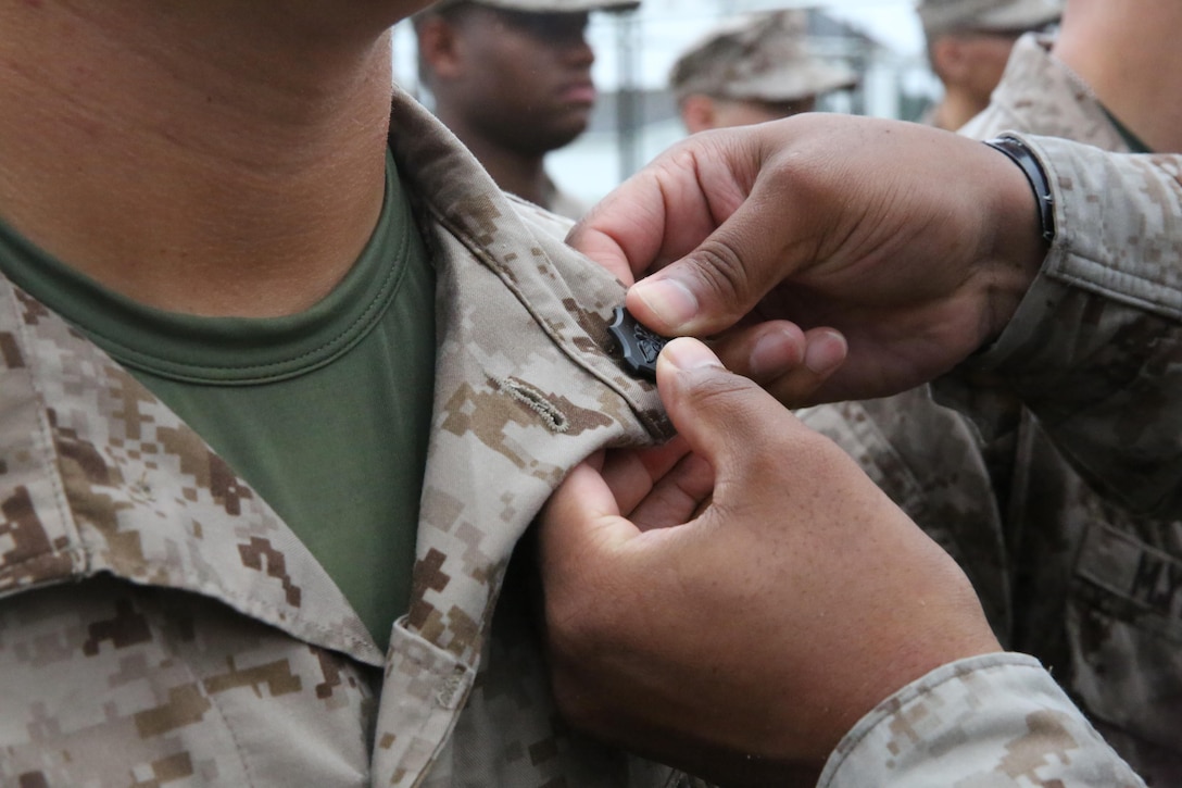 Sailors with the Field Medical Training Battalion receive their shields after an eight-mile hike aboard Camp Johnson, Oct. 8.


