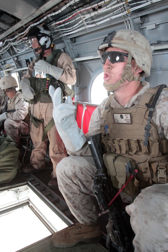 MARINE CORPS BASE CAMP PENDLETON, Calif. – Lance Cpl. Zachary A. Barren, rifleman, Kilo Company, 3rd Battalion, 5th Marine Regiment, gives a warning to other Marines as their helicopter approaches an objective area during fast rope training here, Oct. 9, 2013.