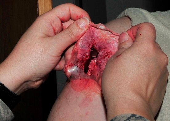 After an actor gets a simulated injury for self-aid and buddy care training, the fake wound can be easily removed. SABC training can be applied to potential combat or emergency situations. (U.S. Air Force photo by Senior Airman Ashley Nicole Taylor/Released)