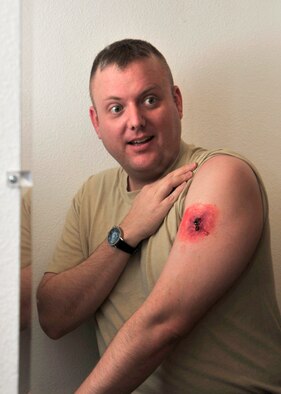 Master Sgt. David Herron, 354th Medical Group dental flight chief, inspects his fake gunshot wound Oct. 2, 2013, Eielson Air Force Base, Alaska. During exercises, moulage actors help Icemen become more proficient in the techniques associated with self-aid and buddy care. (U.S. Air Force photo by Senior Airman Ashley Nicole Taylor/Released)