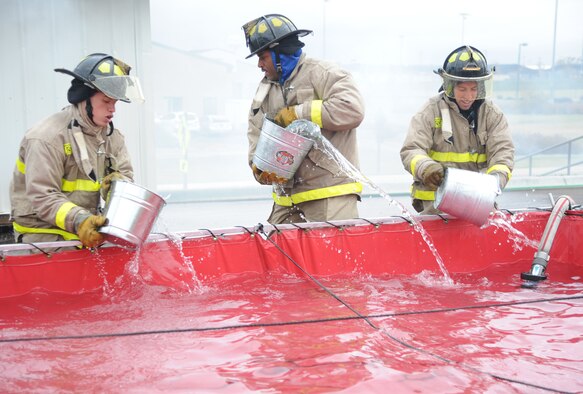 (From left to right) 2nd Lt. David Briggs, Staff Sgt. Walter Falls and Senior Airman Jeremy Flores, all 341st Force Support Squadron members, fill buckets with water at the Bucket Brigade station during the Annual Fire Muster competition on Oct. 11.  Briggs, Falls and Flores, along with their teammate Tech. Sgt. Pete Jernigan (not pictured) represented the 341st FSS during the competition and ultimately took the fastest time of the event.  (U.S. Air Force photo/Senior Airman Cortney Paxton)