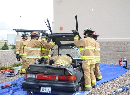 Airmen from Malmstrom’s Fire Department push forward the top of a car during an auto extrication demonstration at the Base Exchange on Oct. 11.  The demonstration was done in conjunction with Fire Prevention Week to show Team Malmstrom members the value of fire fighters across the nation.  (U.S. Air Force photo/Senior Airman Cortney Paxton)