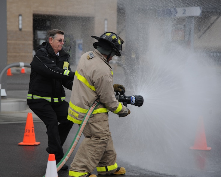 Daniel Dodson, 341st Civil Engineer Squadron deputy fire chief, helps Maj. Eric Doggett, 341st Medical Support Squadron Logistics and Readiness Flight commander, switch the fire hose to a stream.  Doggett and three other members made up a team of 341st MDSS personnel during the Annual Fire Muster competition on Oct. 11 at the Base Exchange.  (U.S. Air Force photo/Senior Airman Cortney Paxton)