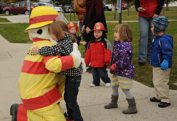 Sparky the Fire Dog hugs children at the Child Development Center on Oct. 9 in celebration of Fire Prevention Week at Malmstrom Air Force Base. During the tour, children had the opportunity to explore the 341st Civil Engineer Squadron’s fire truck and learn about how to prevent fires. (U.S. Air Force photo/Senior Airman Katrina Heikkinen)